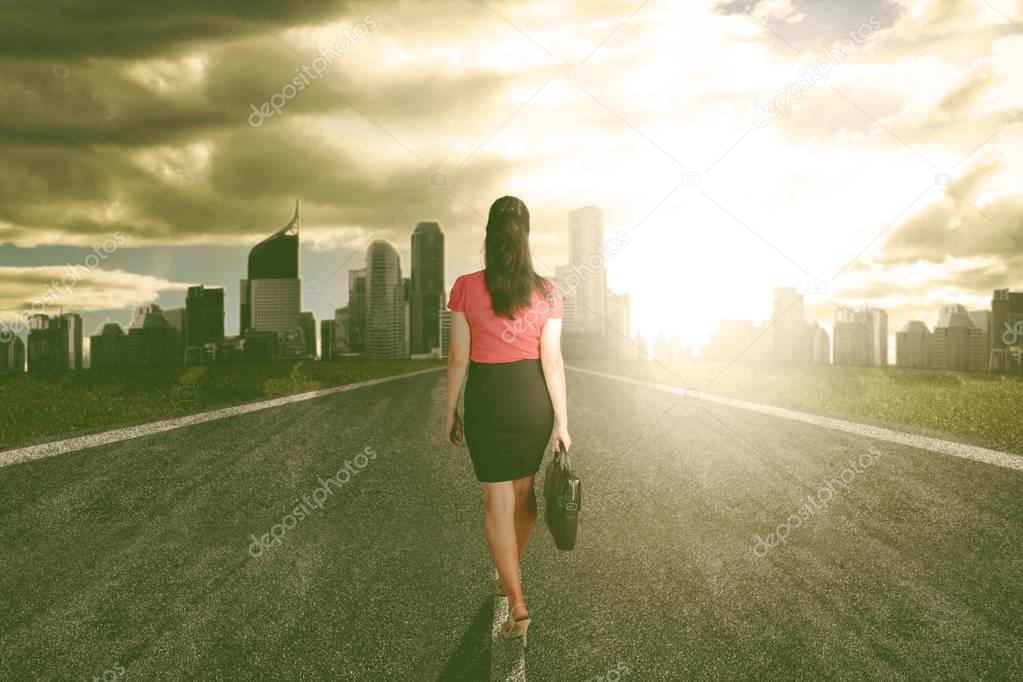 Success business woman walk towards the light heading to the city