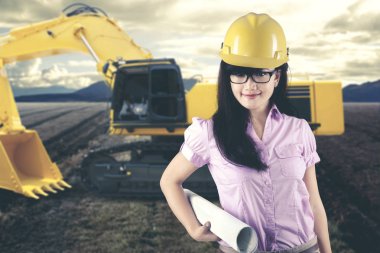 Güzel kadın mimar blueprint bir inşaat alanında bir traktöre yanındaki ile