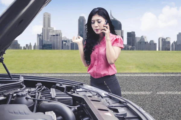 Upprörd affärskvinna talar i telefon ber om hjälp att fixa trasiga ner bil — Stockfoto