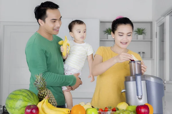 Mor förbereder juice med far och dotter i ett modernt kök — Stockfoto