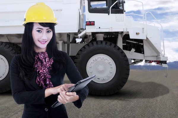 Kolen mijn ingenieur dragen van veiligheidshelm ingedrukt te houden een klembord voor een grote witte mijnbouw vrachtwagen — Stockfoto