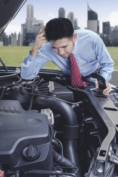 Stressed Asian businessman checking the damaged car engine