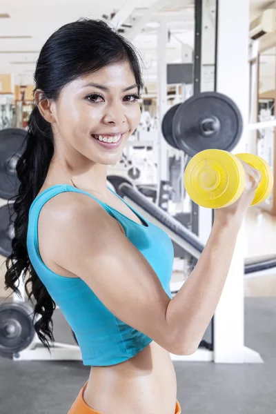 Beautiful asian woman smiling to camera while lifting dumbbell — Stock Photo, Image
