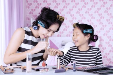 Genç Asyalı anne ve kızı ile saç curlers oje yapıyorsun