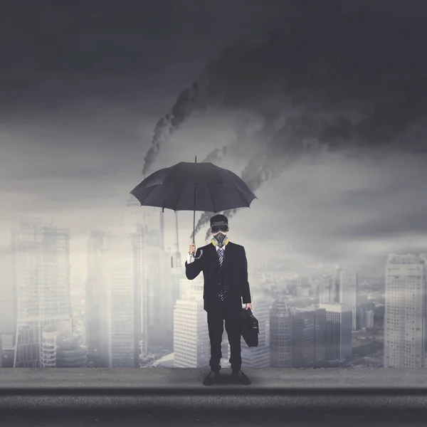 Young businessman with umbrella on the rooftop — Stock Photo, Image