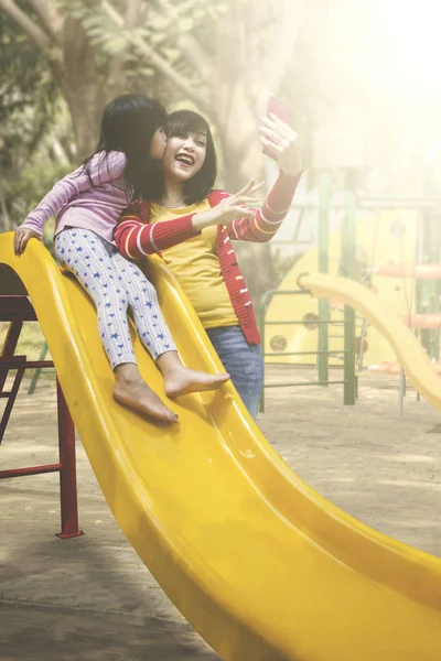 Mãe tomando selfie com sua filha em um playground — Fotografia de Stock