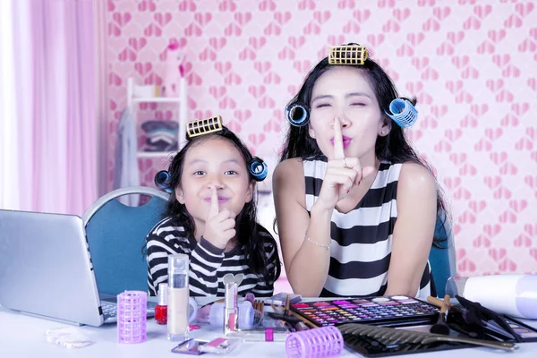 Mère et fille ludiques avec boucleur de cheveux montrant silence geste — Photo