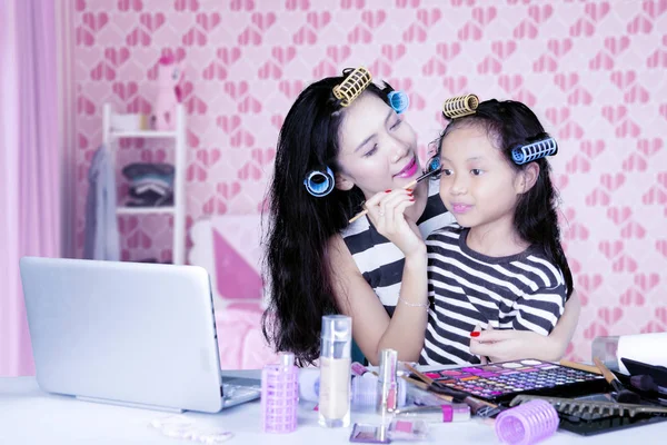 Mère et fille avec boucleur de cheveux regarder tutoriel de maquillage sur ordinateur portable — Photo