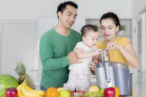 Filha bonito aprender a fazer suco de frutas com os pais — Fotografia de Stock