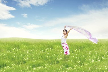 Kumaş üzerinde yeşil çayır tutan kaygısız güzel Asyalı kadın