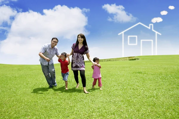 Familia feliz con símbolo de la casa en el prado —  Fotos de Stock