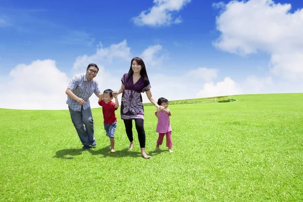 Família feliz correndo no prado — Fotografia de Stock