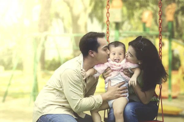 Ung familj porträtt av far och mor kysser sin dotter. — Stockfoto