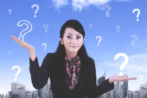 Confused female worker with question marks — Stock Photo, Image