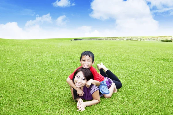 Schöne Frau spielt mit ihrem Sohn im Park — Stockfoto