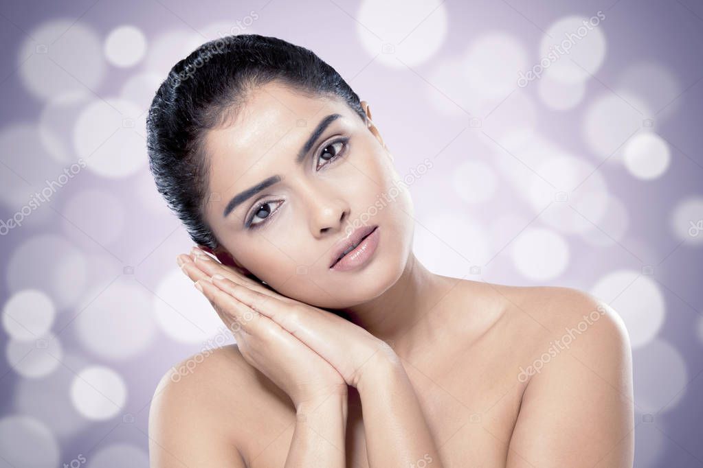 Beautiful Indian woman with healthy skin against blurred lights background.