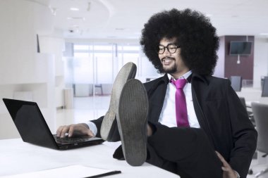 Afrika kökenli Amerikalı işadamı laptop ile çalışma masasında ayaklı