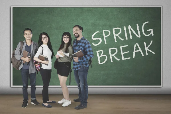 Diversidade estudantes de pé com texto de férias de primavera — Fotografia de Stock