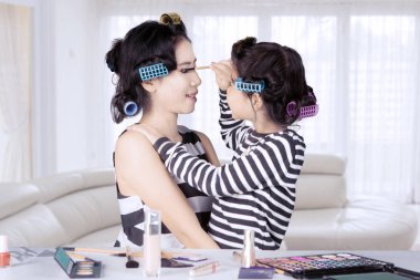 Genç Asyalı anne ve kızı ile saç curlers göz kaşları evde şekillendirme