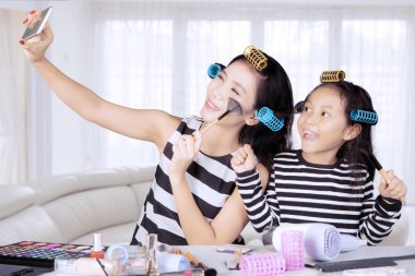Genç Asyalı anne ve kızı ile saç curlers selfie yatak odasında alıyor