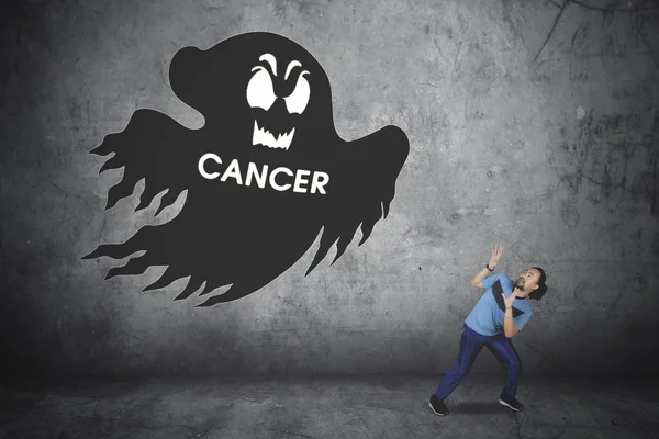 Sporty man with cancer word and ghost — Stock Photo, Image