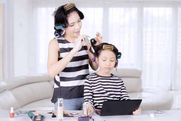 Молода азіатська мати і дочка з ліфчиками для волосся грають з макіяжем у спальні — стокове фото