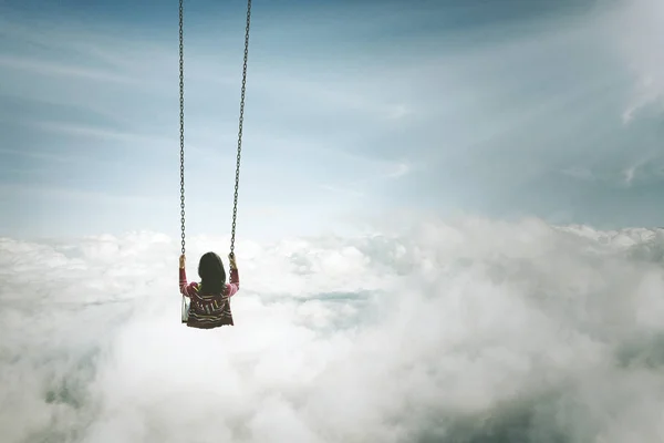 Самотня молода жінка з гойдалками над хмарою — стокове фото