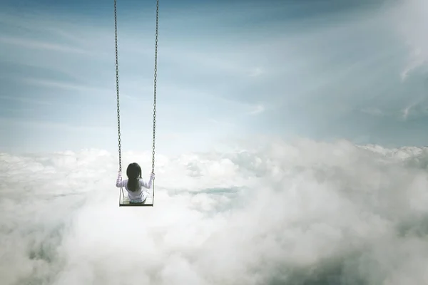 Einsames Mädchen sitzt auf der Schaukel über Wolken — Stockfoto