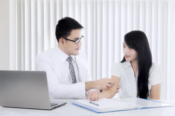 Asiatiska läkare undersökande kvinnlig patient med stetoskop — Stockfoto