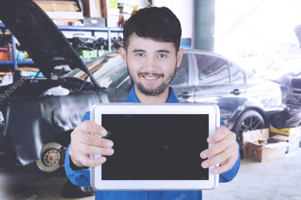 Young friendly mechanic holding digital tablet