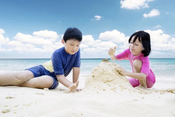 Due bambini che fanno castello di sabbia sulla spiaggia — Foto Stock