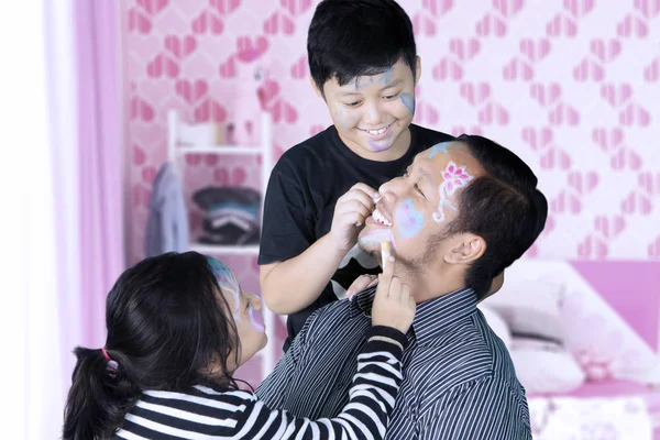 Dos niños pintándole la cara a su padre —  Fotos de Stock