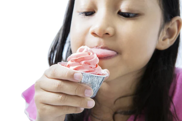 Little girl licking cream of tasty cupcake — Stock Photo, Image