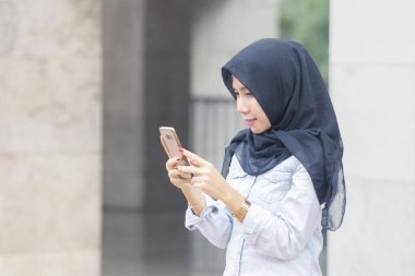 Bir cep telefonu kullanan genç Müslüman kadın