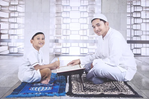 Padre guía a su hijo a leer el Corán — Foto de Stock