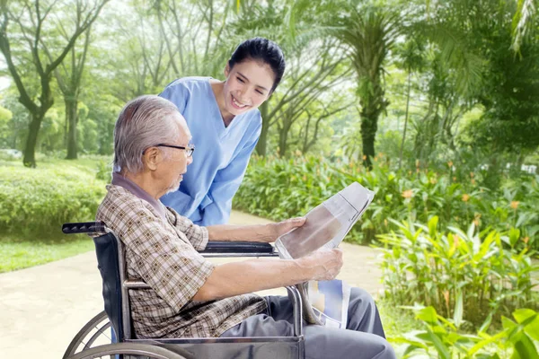 Uomo anziano rilassante con il suo caregiver — Foto Stock