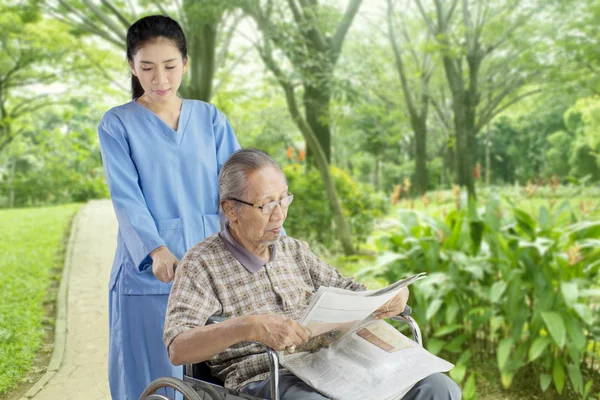 노인 간호사와 함께 신문 읽기 — 스톡 사진
