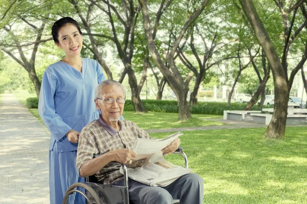 Cheerful nurse with elderly man in the park — Stock Photo, Image