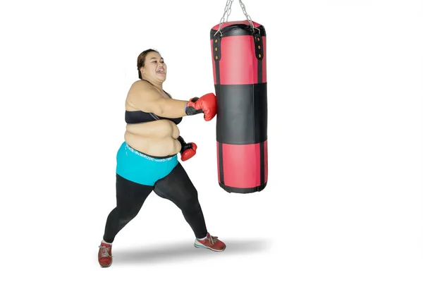 Obeso mulher batendo um saco de boxe no estúdio — Fotografia de Stock