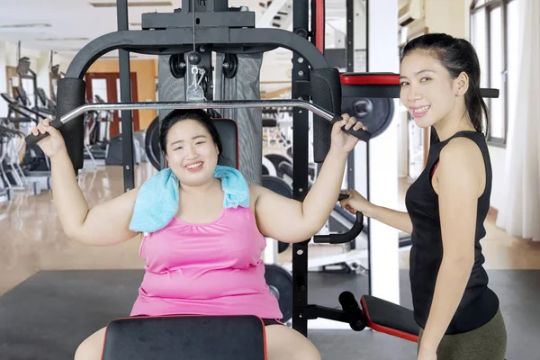 Dicke Frau und ihr Trainer lächeln im Fitnessstudio — Stockfoto