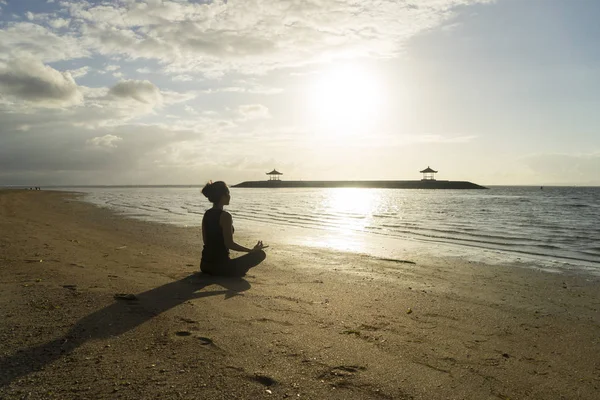 Молодая женщина медитирует на пляже Санур — стоковое фото