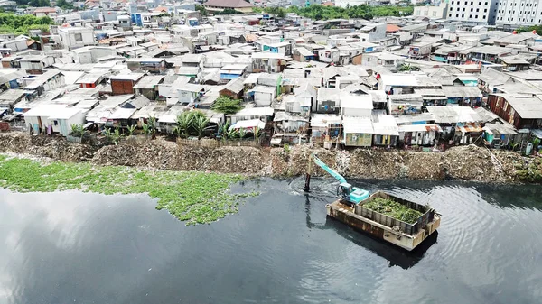 Bairro da favela e uma escavadora à beira do lago — Fotografia de Stock