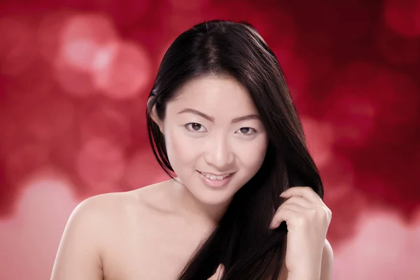Όμορφη κινεζική γυναίκα με υγιή μαλλιά θολή φόντο κόκκινο — Φωτογραφία Αρχείου