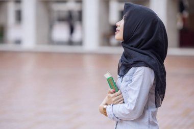 Pretty girl carrying a Quran in the mosque clipart