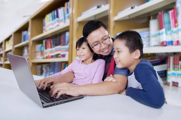 Père et les enfants apprennent en ligne ensemble dans la bibliothèque — Photo