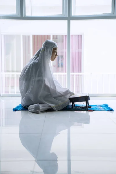 Mulher muçulmana lendo Alcorão perto da janela — Fotografia de Stock