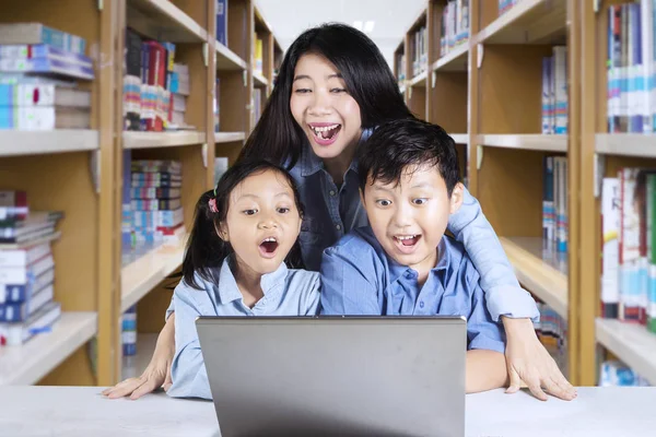 Profesor y estudiantes sorprendidos con un ordenador portátil — Foto de Stock