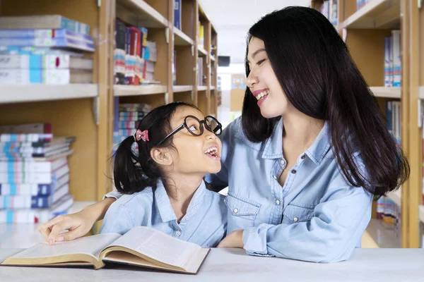 Klein meisje in gesprek met de leraar in de bibliotheek — Stockfoto