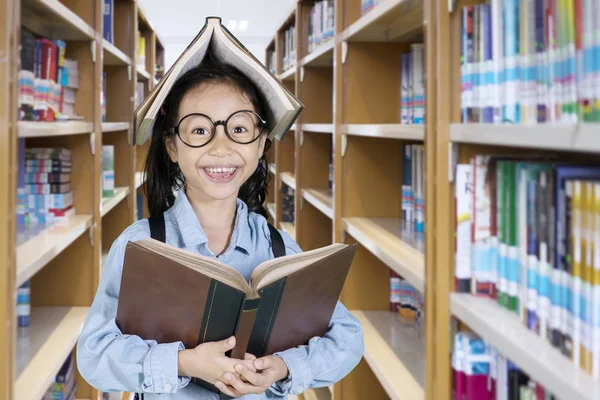 Carino studentessa con un libro sopra la testa — Foto Stock