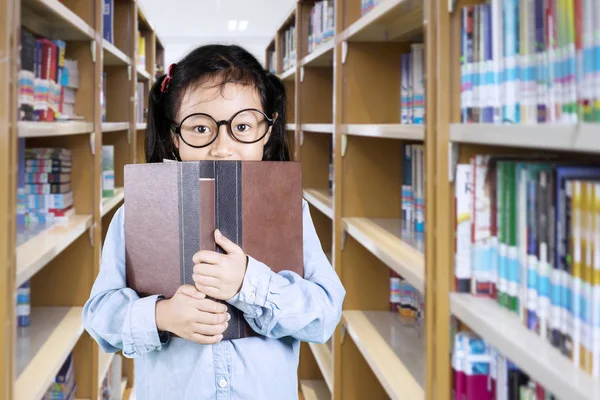 Süße Schulmädchen bedeckt ihr Gesicht mit einem Buch — Stockfoto